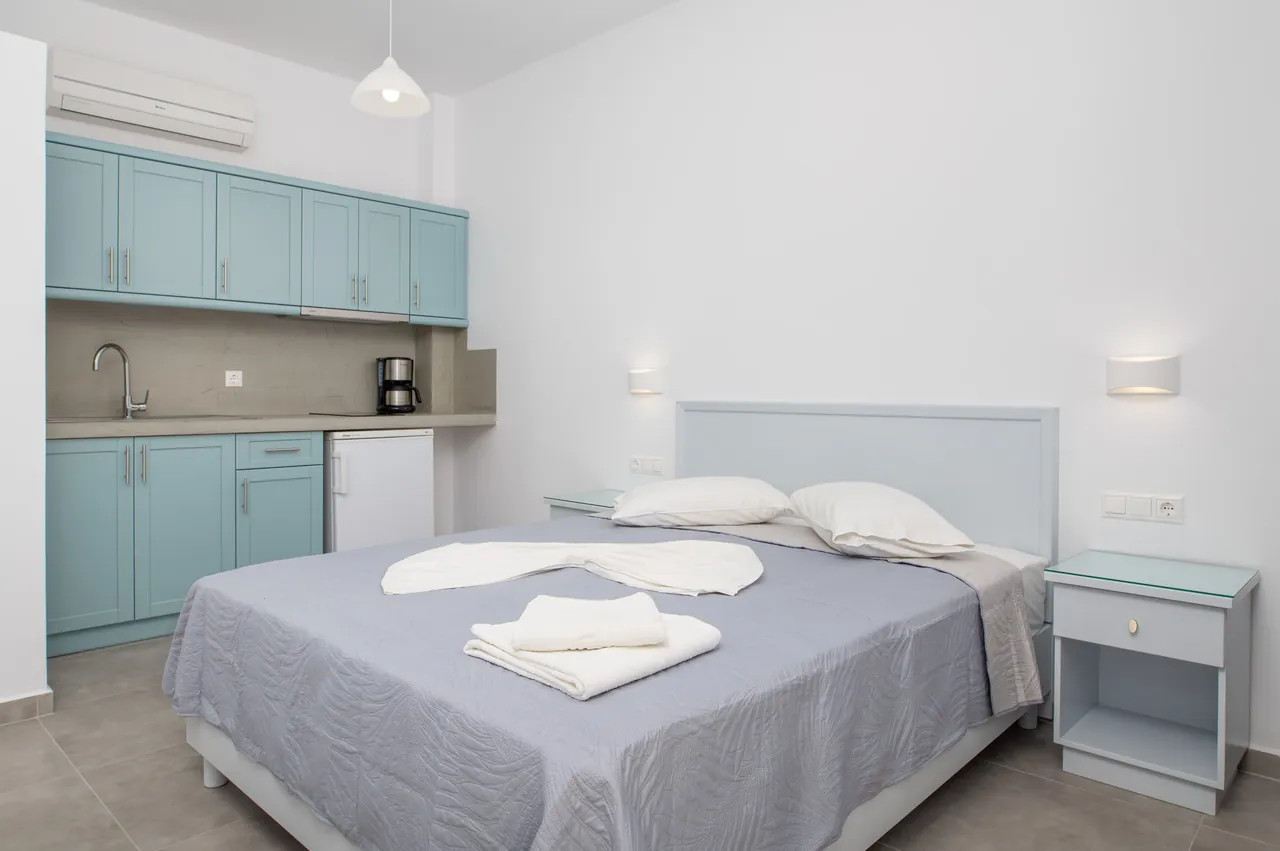 Renovated studio with a double bed, aqua kitchen cabinets and a small dining table
